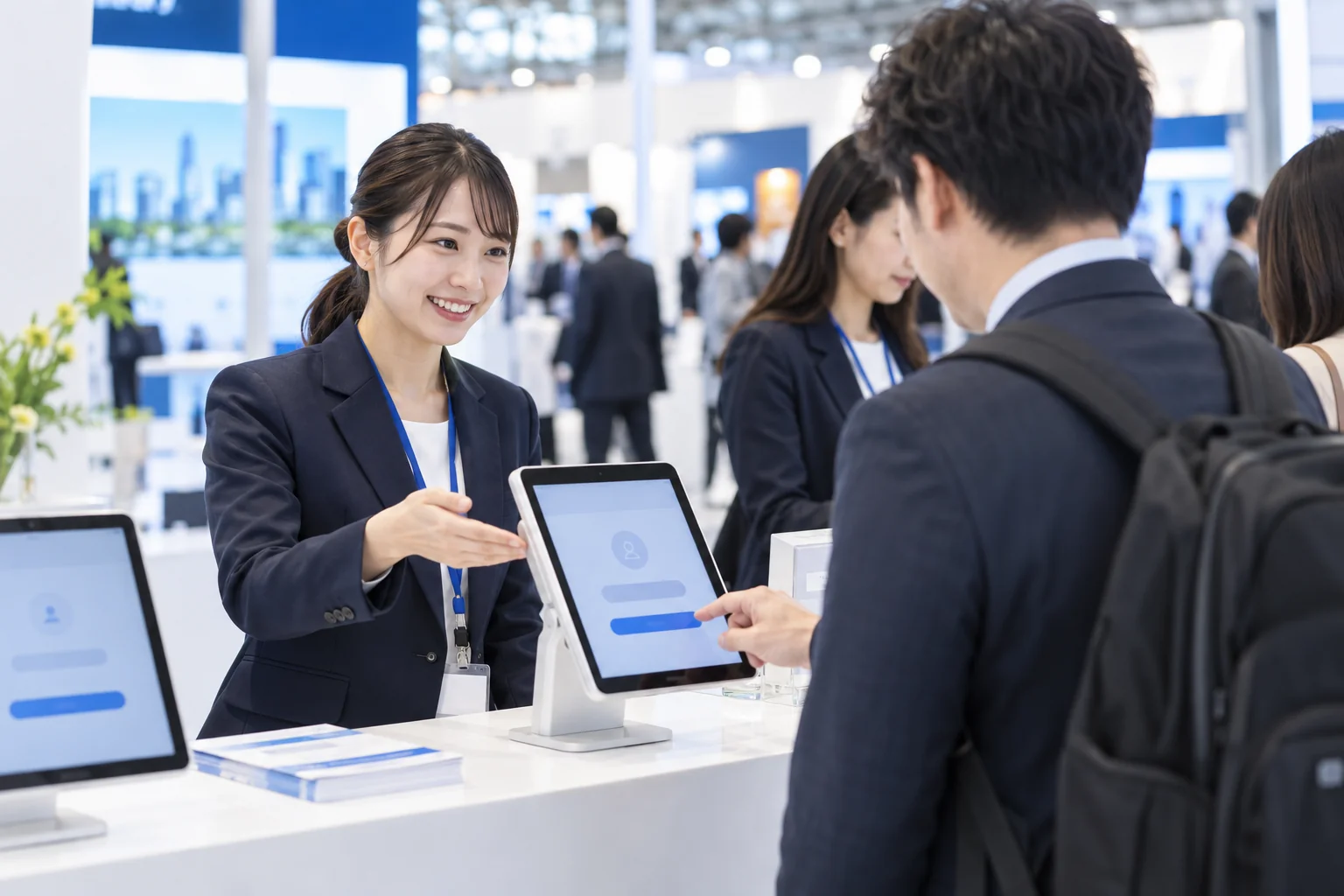 展示会受付でスタンドに設置したタブレットを操作するスタッフ