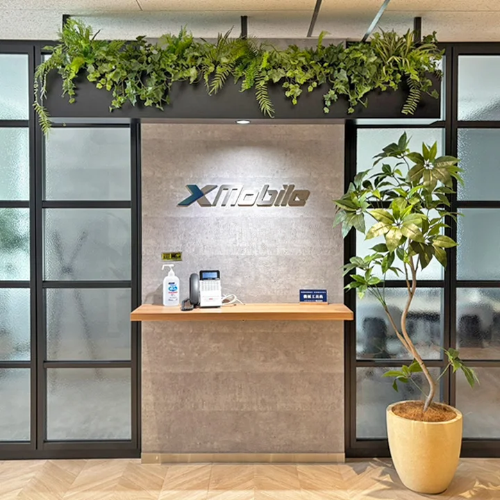 エクスモバイルの受付。社名ロゴと緑の植物がある空間